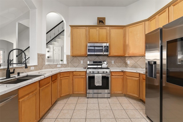 kitchen with tasteful backsplash, sink, light tile patterned floors, and stainless steel appliances