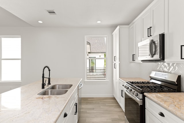 kitchen featuring light stone countertops, white cabinets, appliances with stainless steel finishes, and sink