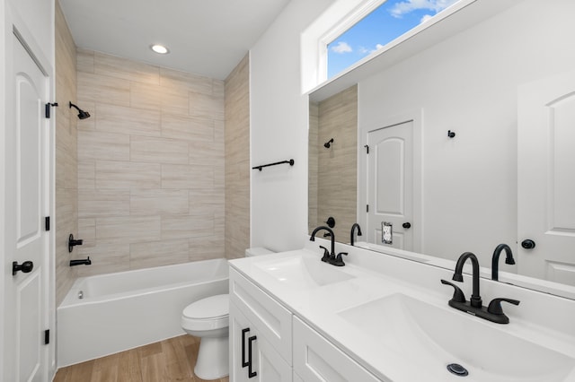 full bathroom featuring vanity, tiled shower / bath combo, toilet, and hardwood / wood-style flooring