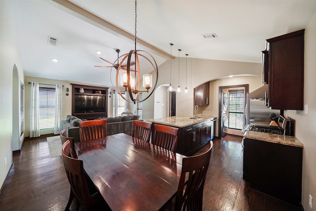 dining area featuring dark wood-type flooring, a chandelier, lofted ceiling with beams, and sink