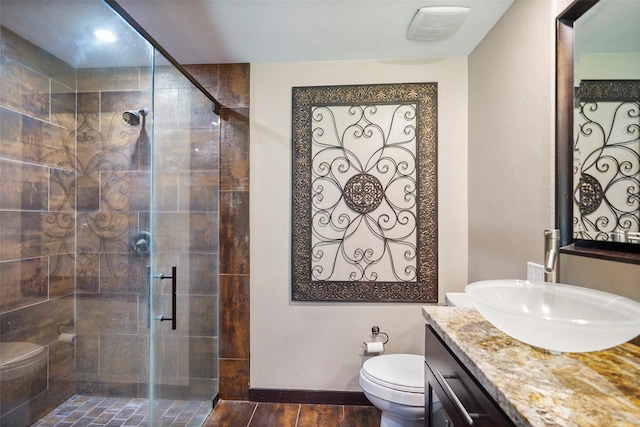 bathroom featuring a shower with door, vanity, and toilet