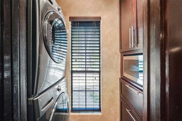 clothes washing area featuring stacked washer and clothes dryer