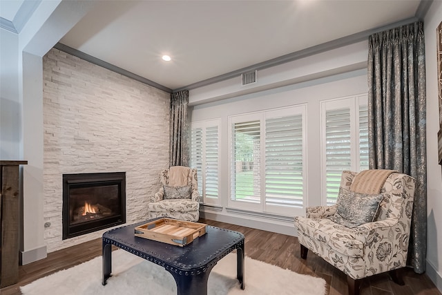 sitting room with crown molding, a stone fireplace, and dark hardwood / wood-style floors