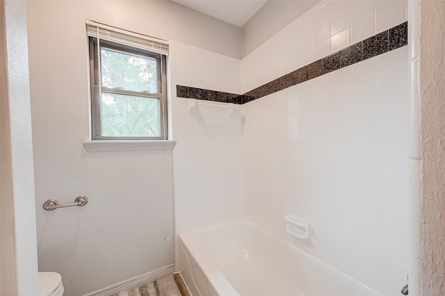 bathroom featuring wood-type flooring, toilet, and tiled shower / bath