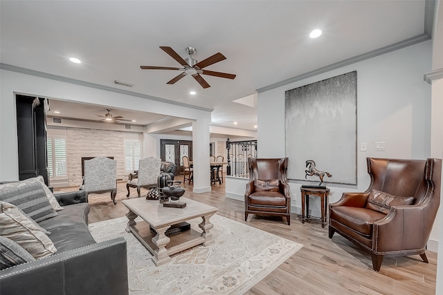 living room with ceiling fan, crown molding, light wood-type flooring, and a healthy amount of sunlight