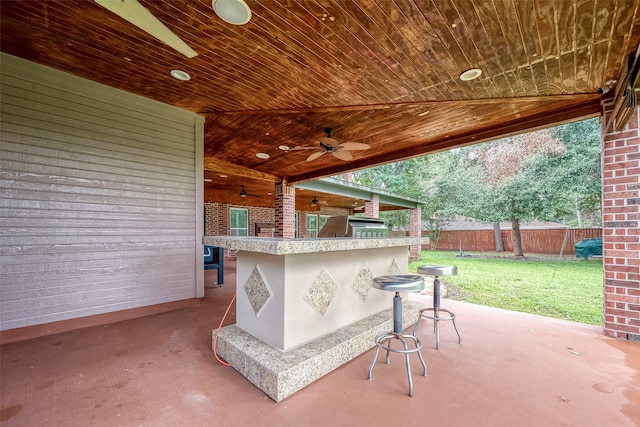 view of patio featuring exterior bar, area for grilling, and ceiling fan