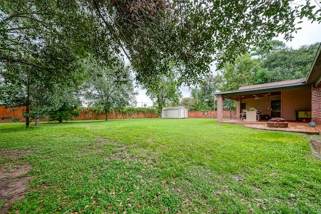 view of yard with a shed, a fire pit, and a patio area