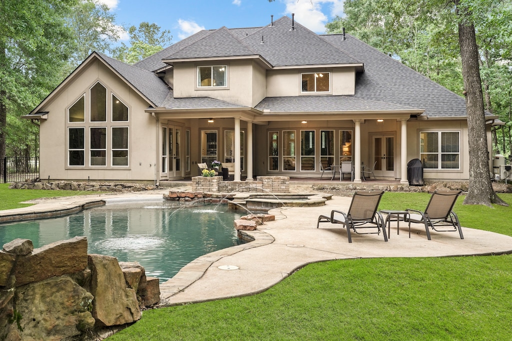 back of property featuring a lawn, a patio, and pool water feature