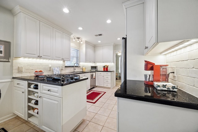 kitchen featuring black gas cooktop, white cabinets, light tile patterned flooring, and sink