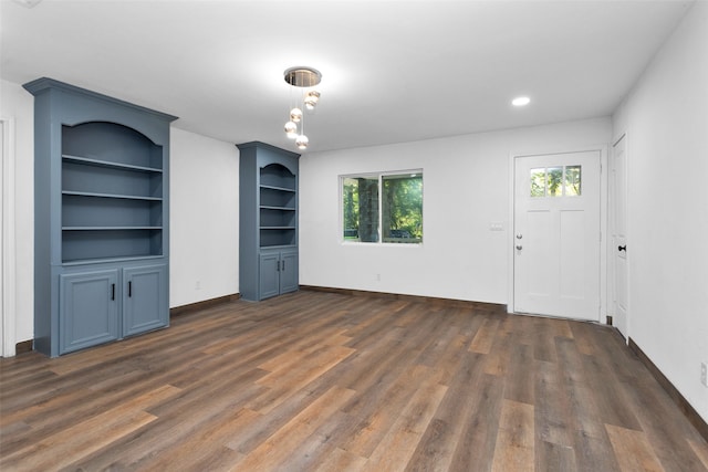 unfurnished living room featuring built in features and dark hardwood / wood-style floors