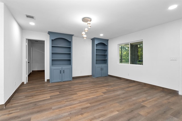 unfurnished living room featuring built in shelves and dark hardwood / wood-style floors