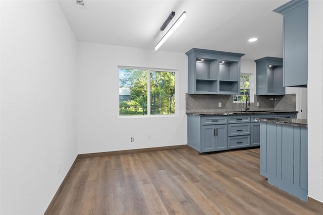 kitchen featuring gray cabinets, hardwood / wood-style flooring, backsplash, and a healthy amount of sunlight