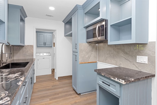 kitchen featuring light wood-type flooring, sink, tasteful backsplash, and washer / dryer