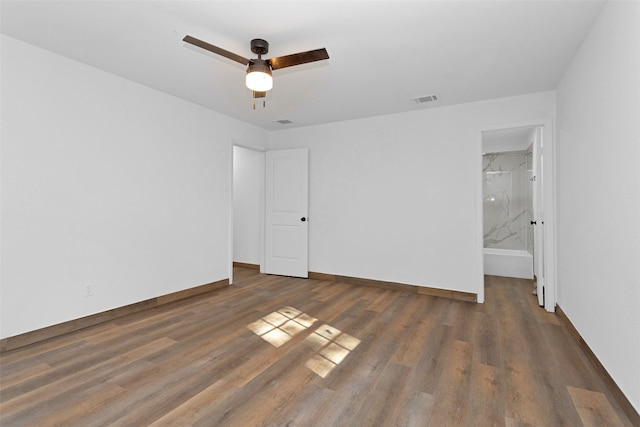 unfurnished bedroom with ensuite bath, dark hardwood / wood-style flooring, and ceiling fan