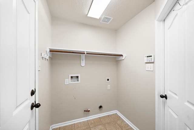 laundry area with tile patterned flooring, washer hookup, hookup for a gas dryer, electric dryer hookup, and a textured ceiling