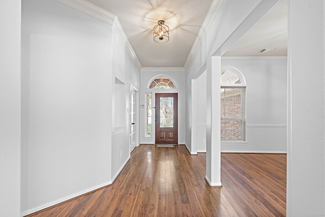 foyer entrance with dark wood-type flooring, crown molding, and a chandelier