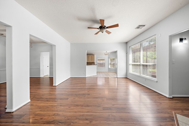 unfurnished living room featuring ceiling fan, a textured ceiling, and dark hardwood / wood-style flooring