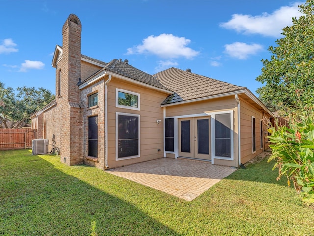 rear view of property featuring central AC unit, a yard, a patio, and french doors