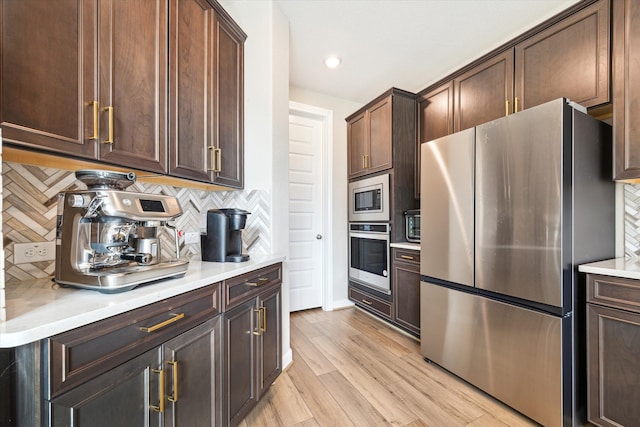 kitchen with stainless steel appliances, decorative backsplash, dark brown cabinetry, and light hardwood / wood-style flooring