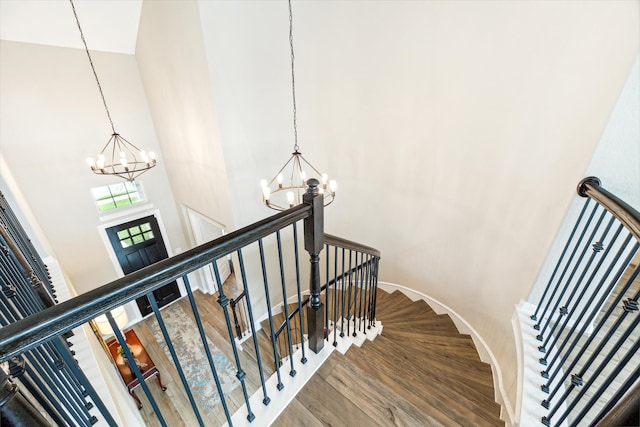 stairs featuring a towering ceiling, a chandelier, and hardwood / wood-style flooring