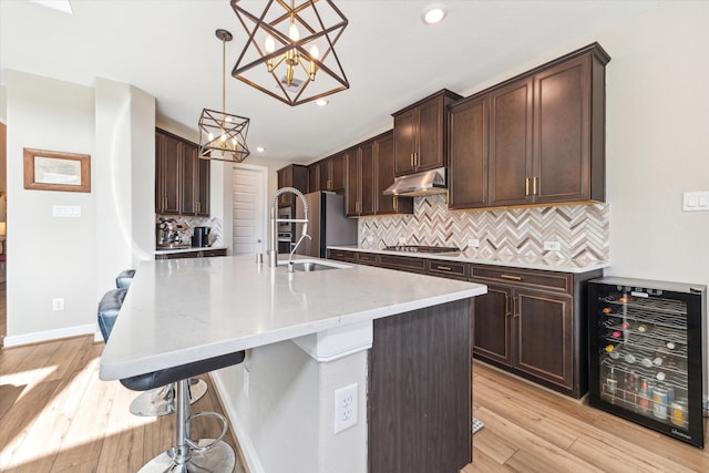 kitchen featuring decorative light fixtures, wine cooler, and a kitchen island with sink