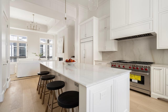 kitchen with white cabinetry, a center island, decorative light fixtures, a breakfast bar area, and high quality appliances