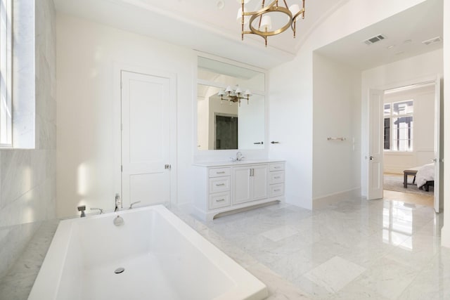 bathroom featuring a chandelier, vanity, and a bathing tub