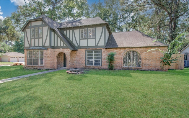 english style home featuring a garage and a front lawn