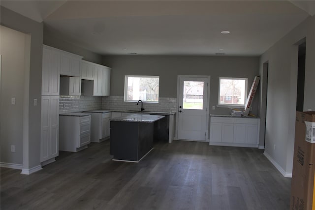 kitchen featuring white cabinetry, a center island, sink, and decorative backsplash