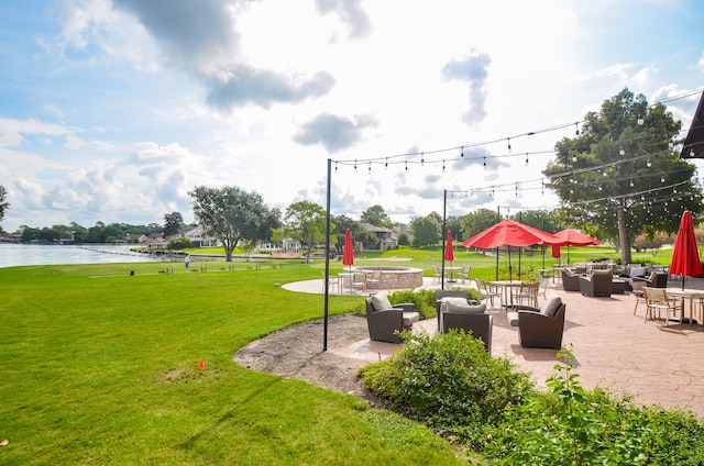 view of community featuring a lawn, a water view, and a patio area