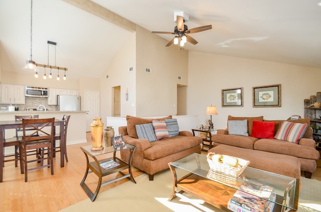 living room with ceiling fan with notable chandelier, light wood-type flooring, and high vaulted ceiling