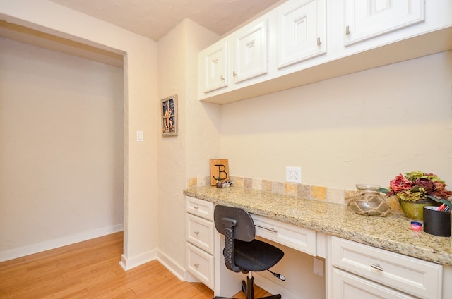 office space featuring built in desk and light hardwood / wood-style flooring