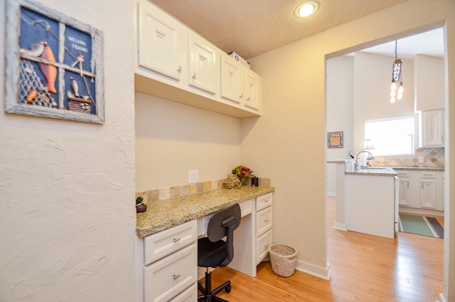 office space with built in desk and light hardwood / wood-style floors