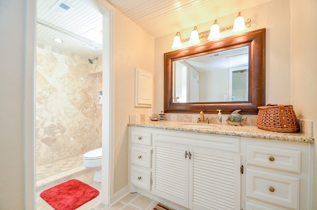 bathroom with vanity, tiled shower, and toilet