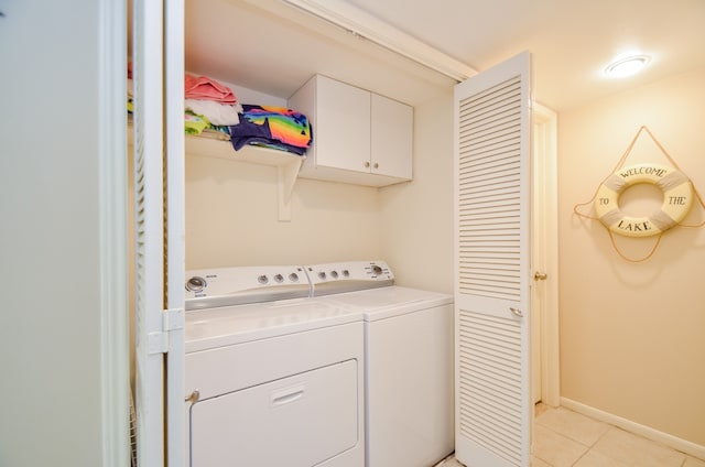 washroom featuring light tile patterned flooring, separate washer and dryer, and cabinets