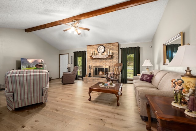 living room featuring lofted ceiling with beams, light wood-type flooring, a healthy amount of sunlight, and a fireplace