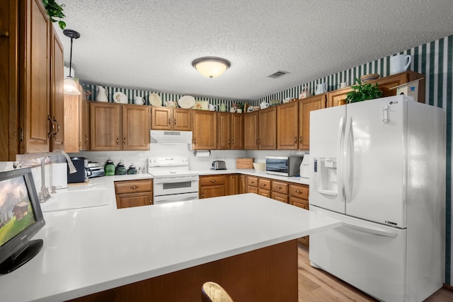 kitchen with light hardwood / wood-style floors, hanging light fixtures, kitchen peninsula, and white appliances