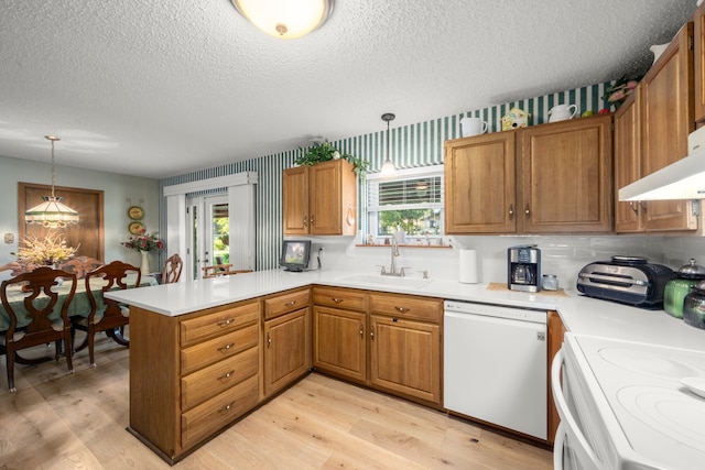 kitchen with kitchen peninsula, pendant lighting, white appliances, and sink