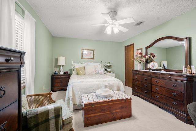 carpeted bedroom featuring ceiling fan and a textured ceiling