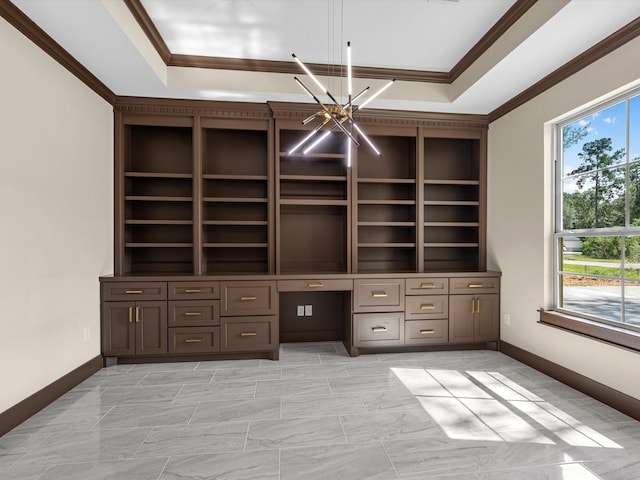 unfurnished office featuring ornamental molding, plenty of natural light, a tray ceiling, and built in desk