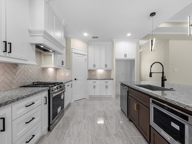 kitchen with decorative light fixtures, sink, white cabinets, light stone counters, and stainless steel appliances