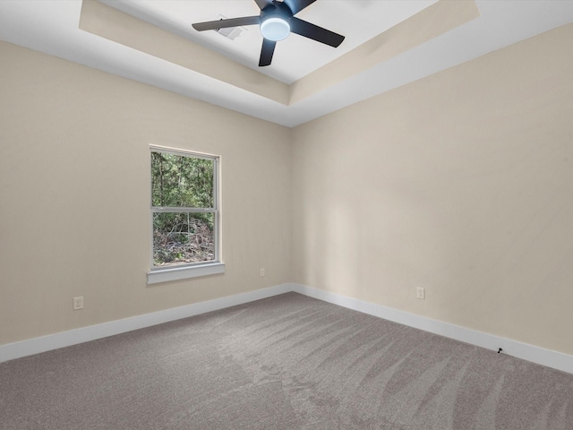 carpeted spare room with ceiling fan and a raised ceiling