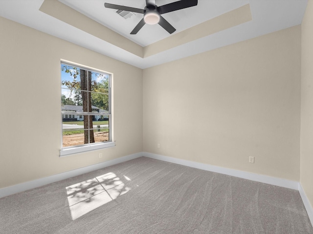 empty room with carpet, ceiling fan, and a tray ceiling