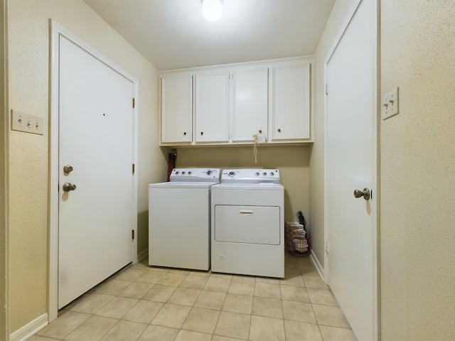 washroom with washing machine and dryer, light tile patterned floors, and cabinets