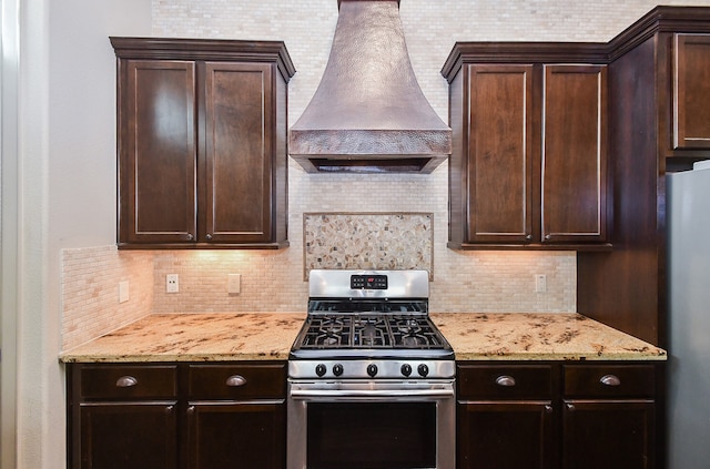 kitchen featuring tasteful backsplash, dark brown cabinetry, stainless steel appliances, and custom exhaust hood