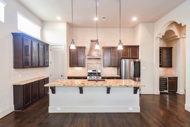 kitchen featuring appliances with stainless steel finishes, pendant lighting, wine cooler, and wall chimney exhaust hood