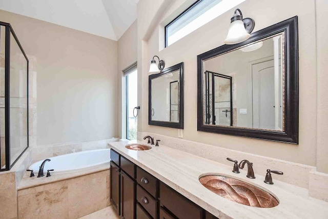 bathroom with vanity, tiled bath, and vaulted ceiling