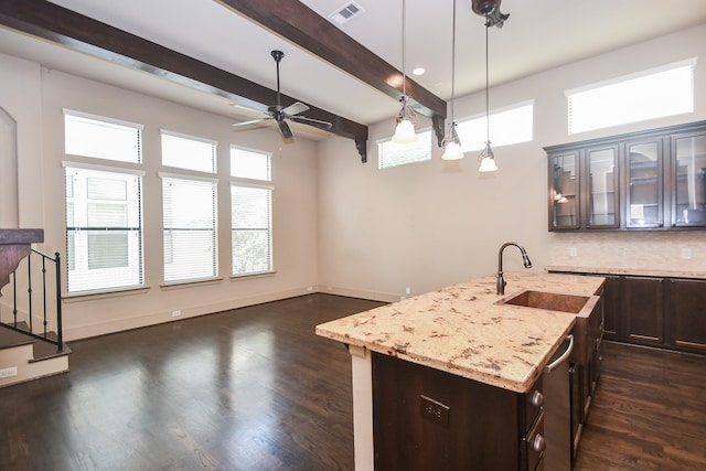 kitchen with plenty of natural light, light stone countertops, sink, and a kitchen island with sink