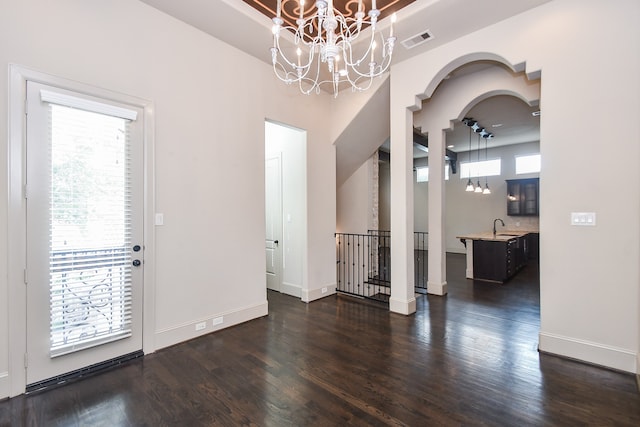 unfurnished dining area with dark hardwood / wood-style floors, an inviting chandelier, and sink