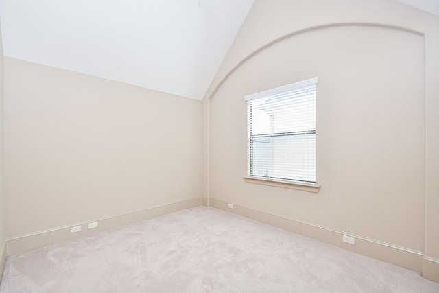 empty room featuring light colored carpet and vaulted ceiling